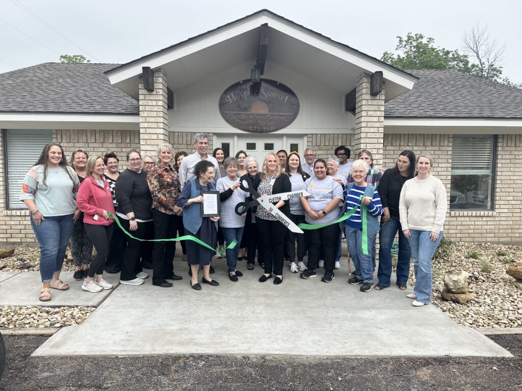 A group of Hospice Sunset staff in front of the new building while cutting the ribbon.